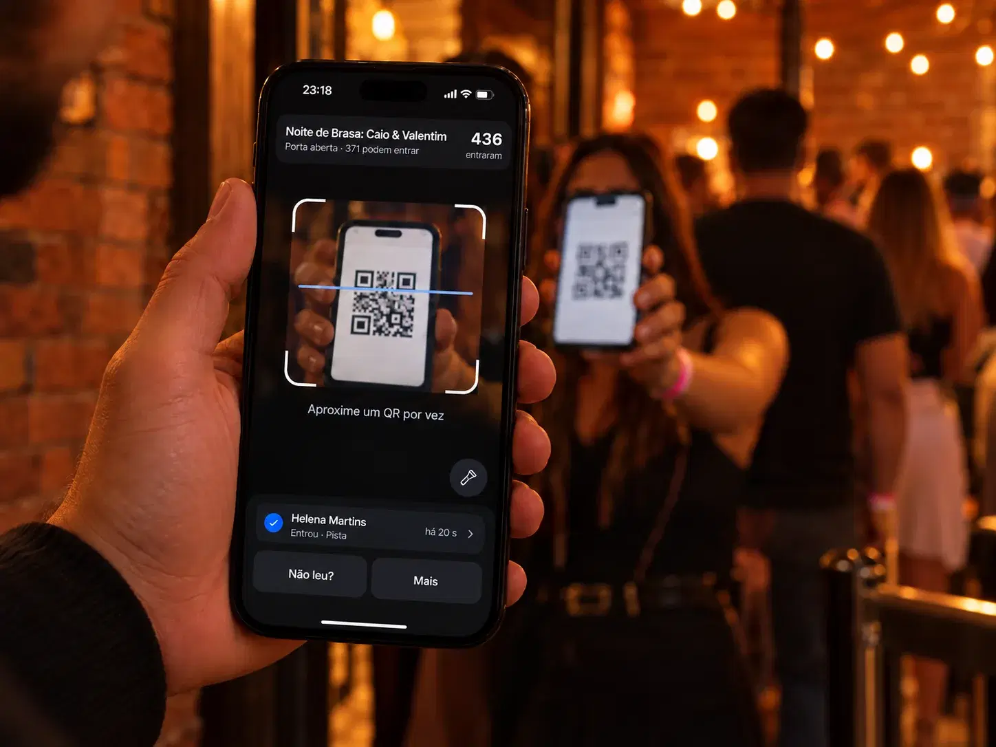 Fiscal na porta do Palco Demo lendo com o celular o QR Code do ingresso de quem chega